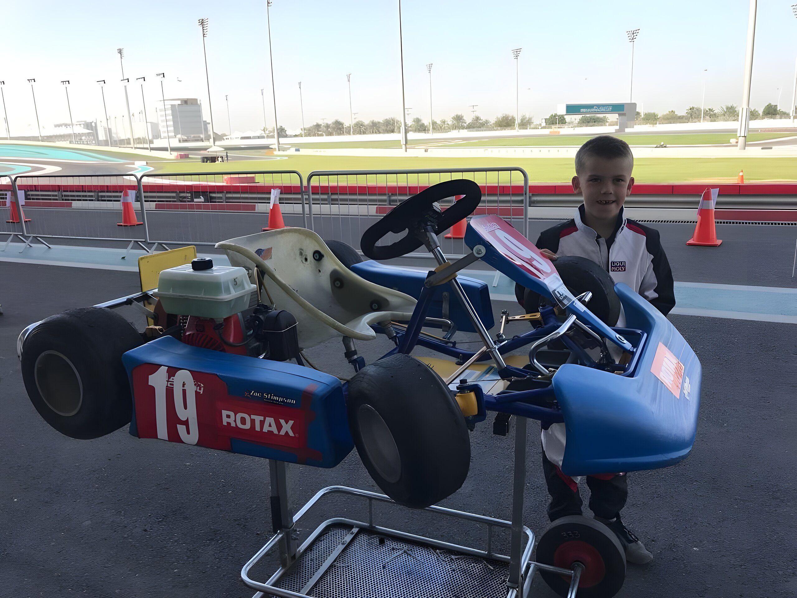 Age six with kart number 19 at the fence, the Formula 1 circuit at Yas Marina stretching out behind