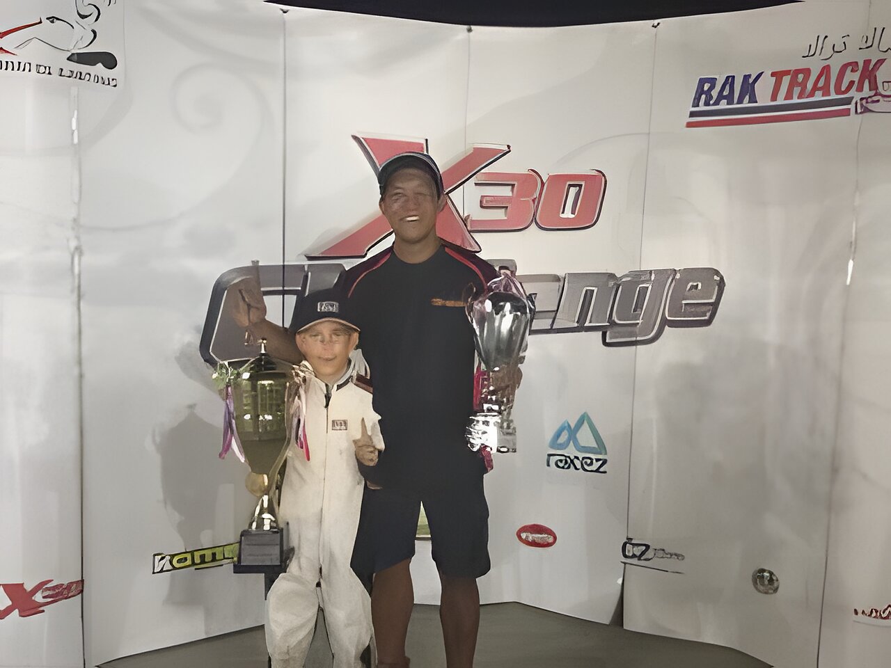 Zac and his coach with both trophies in front of the X30 Challenge board at RAK Track